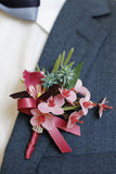 Burgunderfarbene Ball-Corsage am Handgelenk und Herren-Boutonniere mit Perlen